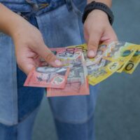 Close-up of a person holding assorted Australian banknotes in their hands.