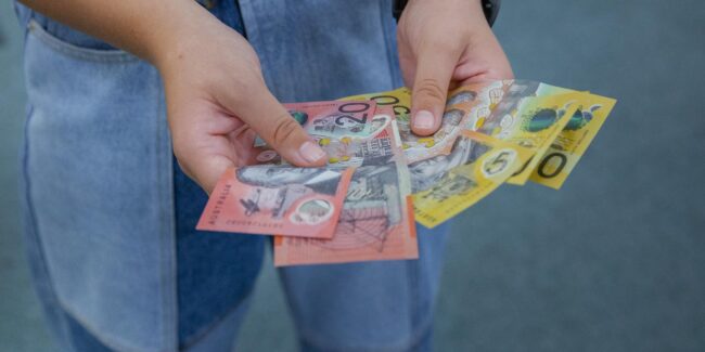 Close-up of a person holding assorted Australian banknotes in their hands.