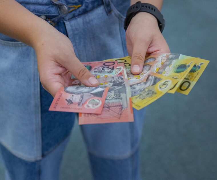 Close-up of a person holding assorted Australian banknotes in their hands.